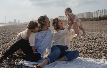Family image on the Brighton beach laughing holding their baby in the air