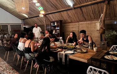 A group of friends enjoying a traditional dinner at a rustic bamboo restaurant with hanging lanterns.