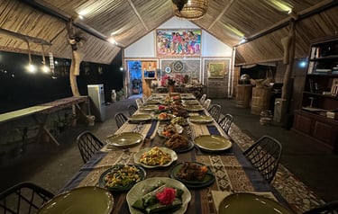 Traditional Indonesian feast served on a long table in a bamboo restaurant with hanging lanterns.
