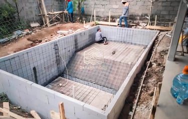 proses pembuatan kolam renang dengan bata merah sebagai penahan beton bagian luar.
