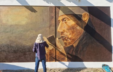 An artist creates a large street art mural of an indigenous shaman smoking a pipe