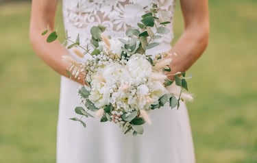 La mariée tient un bouquet de mariée champêtre composé de pivoines blanches, de gypsophile.