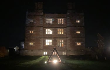 Soulton Hall seen at night with a large, steel pyramid in front