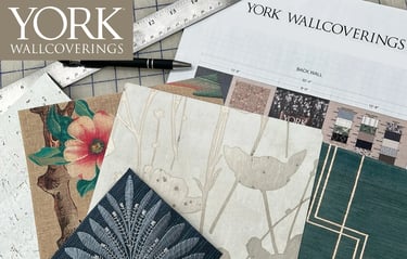 York Wallcoverings designer wallpaper samples with floral and geometric patterns on a project planning desk.
