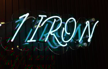 A neon 1IRON sign in an indoor golf simulator venue