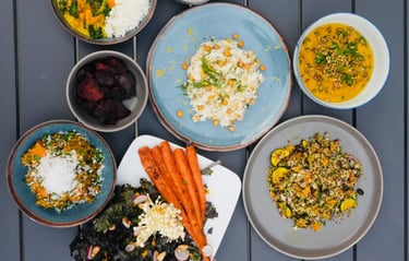 a table with bowls of vegetarian plant-based food and a bowl of vegetables carrots chickpeas