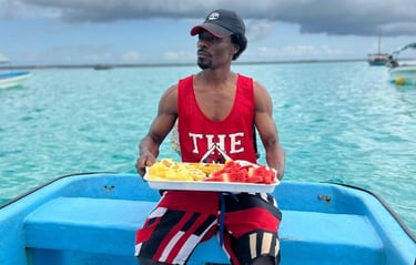 Local Zanzibar tour guide serving fresh fruits on a Mnemba Island day tour boat trip with tourists enjoying the journey