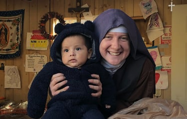 A Franciscan Daughter of Mary and a very cute baby pose for a picture at the Rose garden Mission