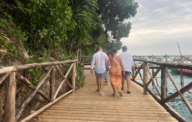 Tourists walking on a wooden bridge along the beach to boats during Prison Island (Changuu Island) tour in Zanzibar