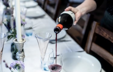 a person pouring wine into wine glasses on a table