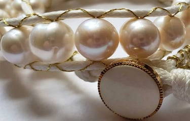 a bracelet with a white pearl and a gold cord