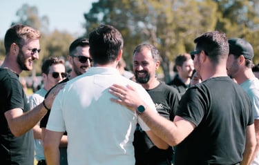 A group of diverse men talking and smiling at a casual outdoor networking event.
