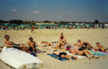 Una foto sgranata di una spiaggia con dei ragazzi stesi sui teli vicino a una barca rovesciata