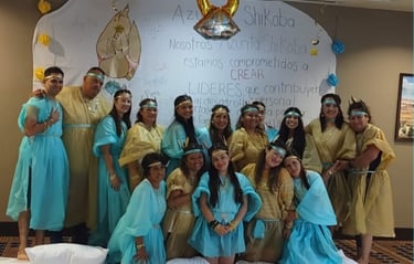 A group of people wearing blue and gold robes posing in front of a white leadership development banner.