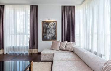 Modern living room featuring a plush sectional sofa, dark wood floors, and elegant purple curtains.