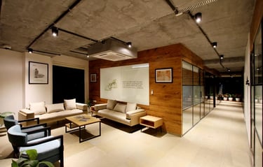 Modern office waiting area with industrial concrete ceilings, wood paneling, and comfortable sofas.