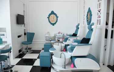 Modern luxury nail salon interior with blue pedicure chairs and foot baths on a black and white checkered floor.