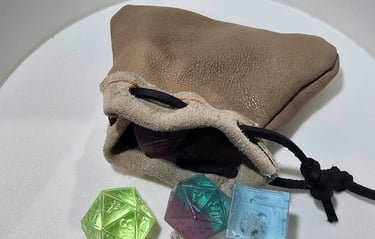 Colorful translucent resin dice spilling out of a handcrafted leather dice bag.
