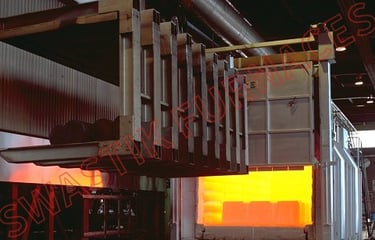 Industrial heat treatment furnace with open door showing glowing orange interior and loading mechanism.