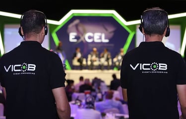 two men in black shirts and headphones are standing in front of a stage