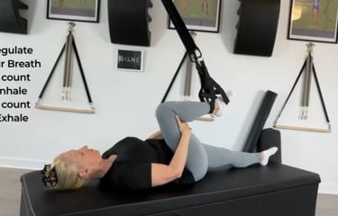 a woman working a yoga pose breathwork as her leg is supported with a suspension trainer