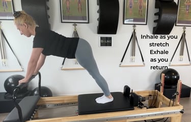 a woman working here ability to perfoming a downward dog on the reformer