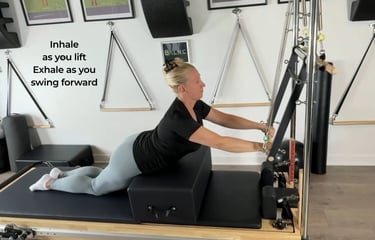 a woman work spine extension with the Pilates Tower Push Through Bar