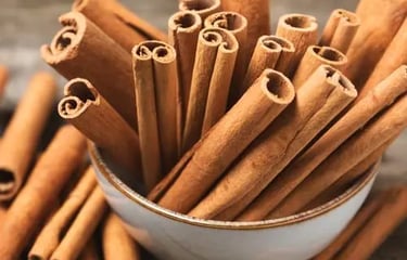 A white bowl filled with aromatic cinnamon sticks on a rustic wooden background.