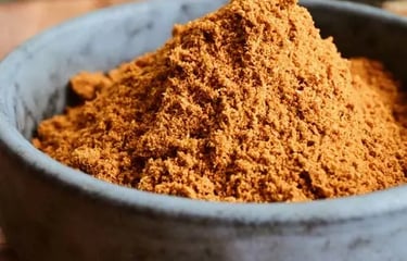 A small stone bowl filled with a heap of finely ground organic cumin spice powder.