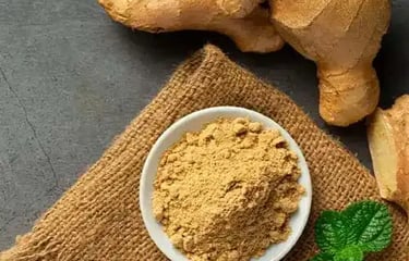 Fresh whole ginger powder organic ground ginger powder in a small bowl on burlap fabric.