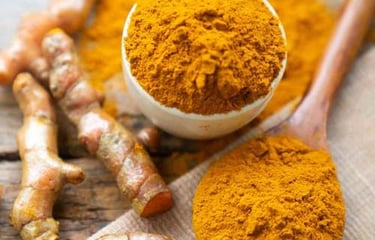 Fresh organic turmeric powder in a small bowl and wooden spoon on a rustic surface.