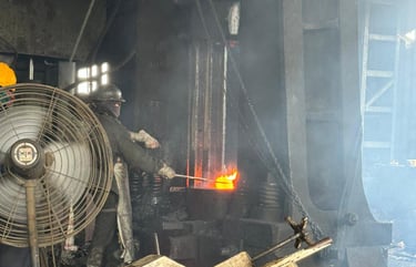 Industrial steel worker using a metal forging press to shape glowing hot molten metal in a factory.