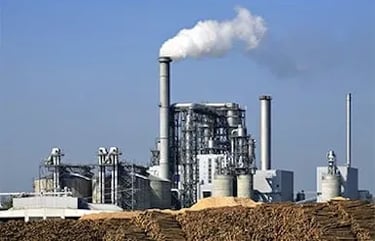 an industry built above the ground with various pipelines ans somke is coming out from one.