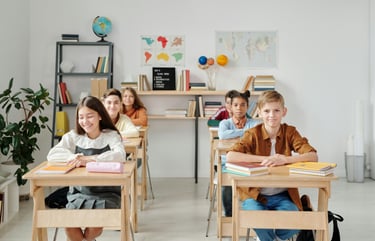 a group of teenagers sitting at desks in a classroom