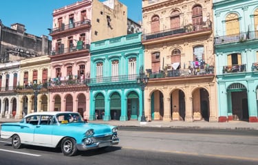 Vintage blue classic car taxi driving past colorful colonial buildings in Havana, Cuba.