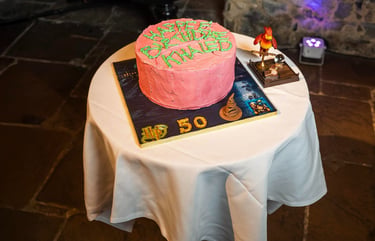 Pink birthday cake on display table in event hall, photographed by Fred Art Studio.