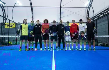 A group of padel players standing with rackets on a blue indoor court for a tournament team photo.