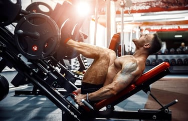 Homem musculoso realizando exercício de leg press na academia com peso elevado.