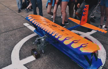 Biplano azul e laranja pousado na pista, na frente de pessoas