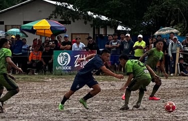 Football players competing in a mud soccer match on a rainy day with spectators watching from the sidelines.