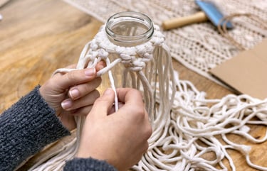 Manos atando un nudo cuadrado con cordón de algodón