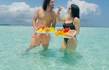 Romantic couple enjoying tropical fruits and feeding each other during Safari Blue Zanzibar island tour and sandbank picnic 
