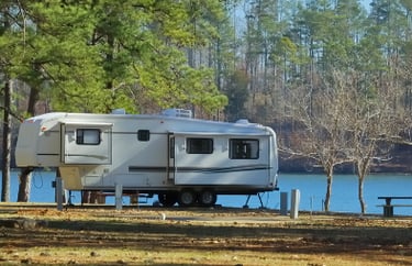 a camper trailer parked on the shore of a lake
