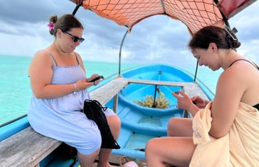 Two tourists relaxing on a boat during a Mnemba Island Zanzibar day tour, preparing for snorkeling adventure