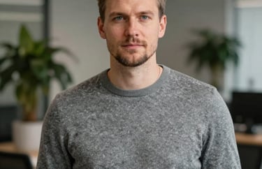 Professional portrait of a man in a grey sweater, modern office environment with blurred plants in the background, Northern European / Baltic / Estonian.