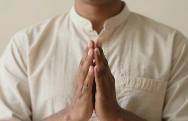 A portrait of a South Asian spiritual practitioner with hands in a mudra position. Wearing a simple cotton tunic, soft focus on the hands, cream background.