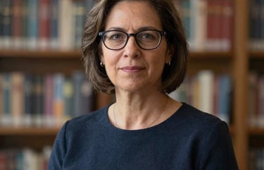 A professional portrait of a woman in her 40s with glasses, looking authoritative and approachable, standing in front of a blurred academic background. North American / US setting.