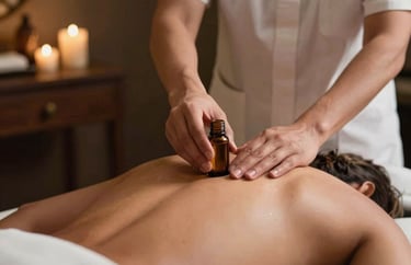 Action shot of a therapist's hands applying essential oil onto a guest's back in a dimly lit, luxury South Asian spa room.
