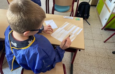 Image d'un élève en activité individuelle qui peint des bâtonnets de bois