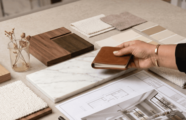 A designer mood board with marble, wood samples, and floor plans for bespoke tailored interior design solutions.